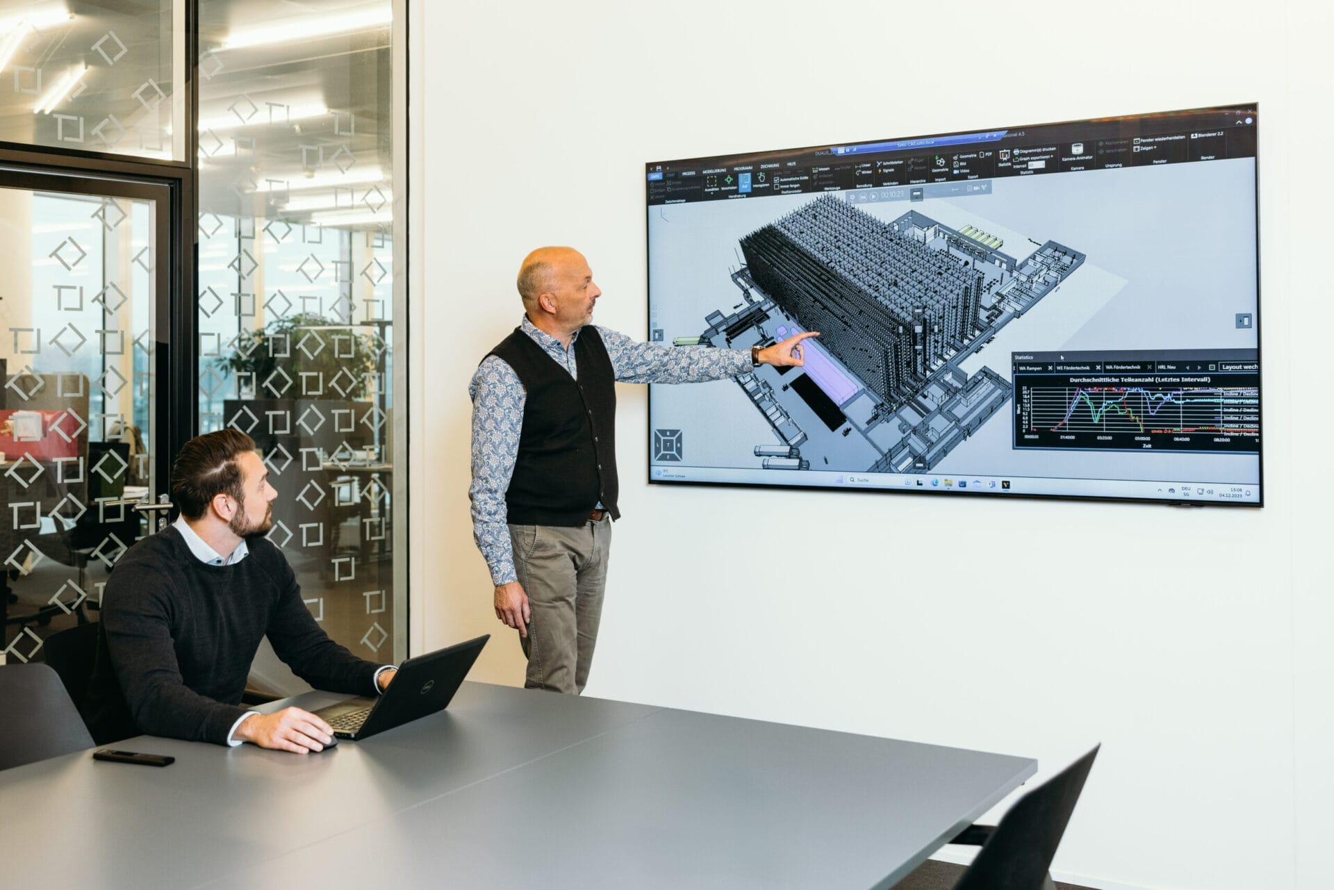 Zwei Mitarbeitende von SOLTIC betrachten eine Simulation in einem Besprechungsraum